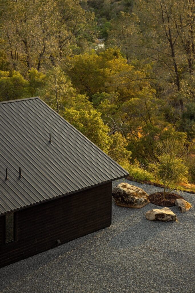 Close-up overhead view of the black corrugated metal roof of Casa Roca next to a grey gravel yard with natural rocks.