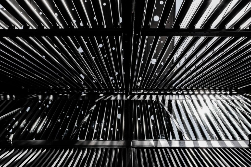 Abstract, high-contrast view of the underside of the George Street Plaza's perforated canopy, showing the dramatic pattern of light filtering through the linear slats and circular openings.