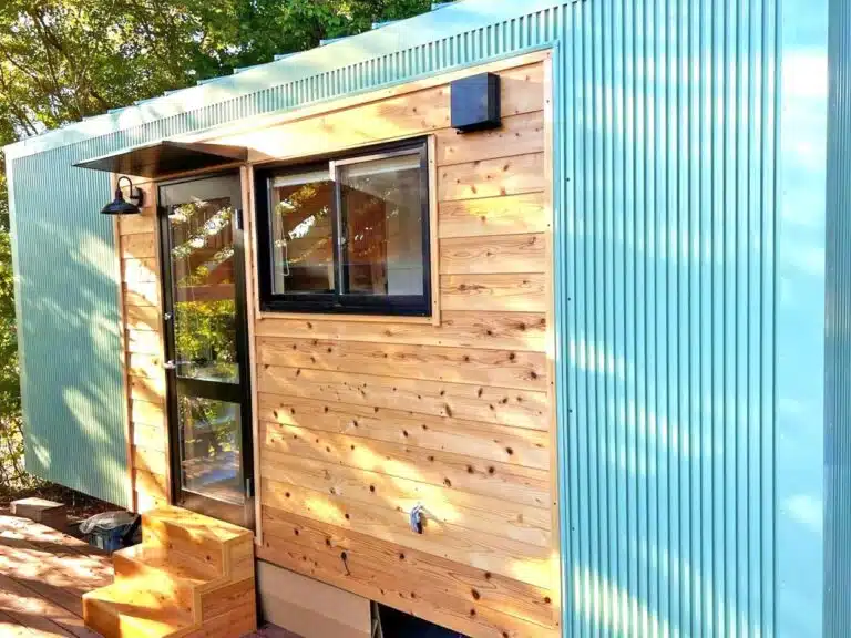 Exterior view of Nozawa tiny house in Japan, featuring wood cladding and light blue corrugated metal siding on sunny day.