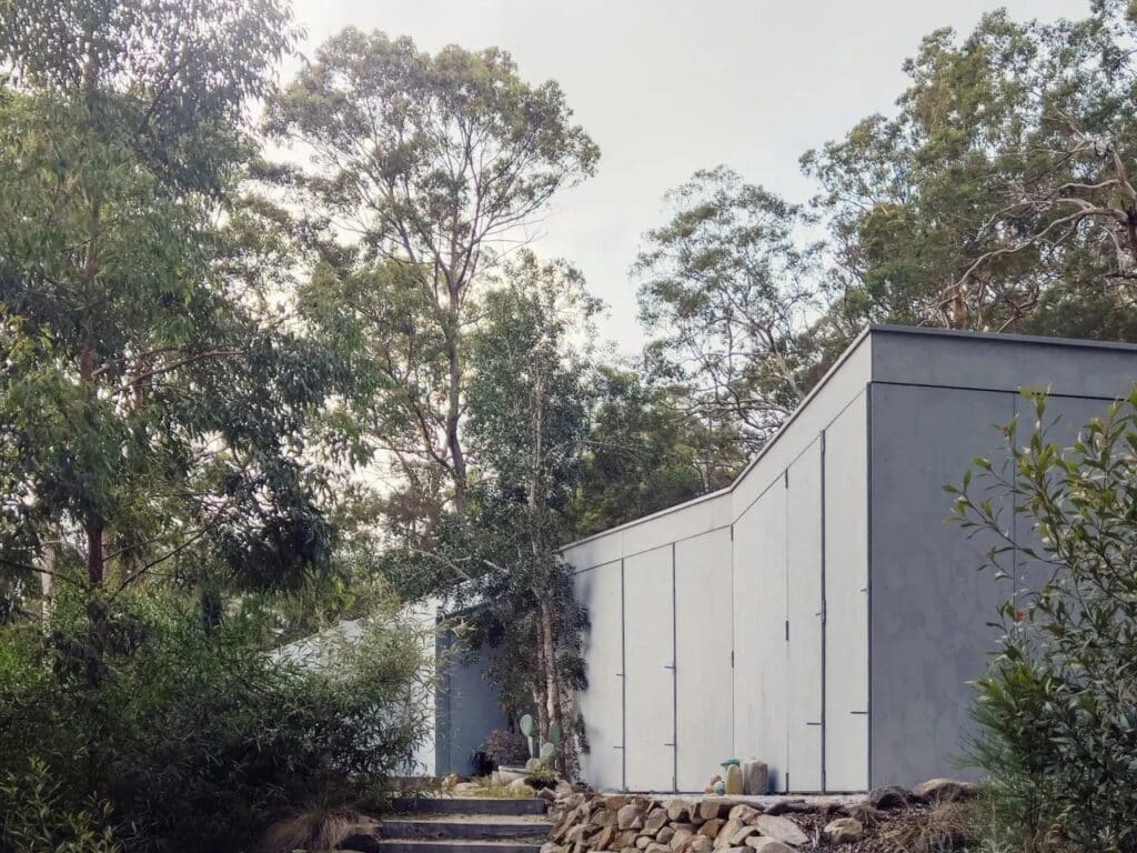 Exterior view of Amongst the Eucalypts holiday home perched among tall eucalyptus trees in New South Wales, highlighting its integration with the forested landscape.