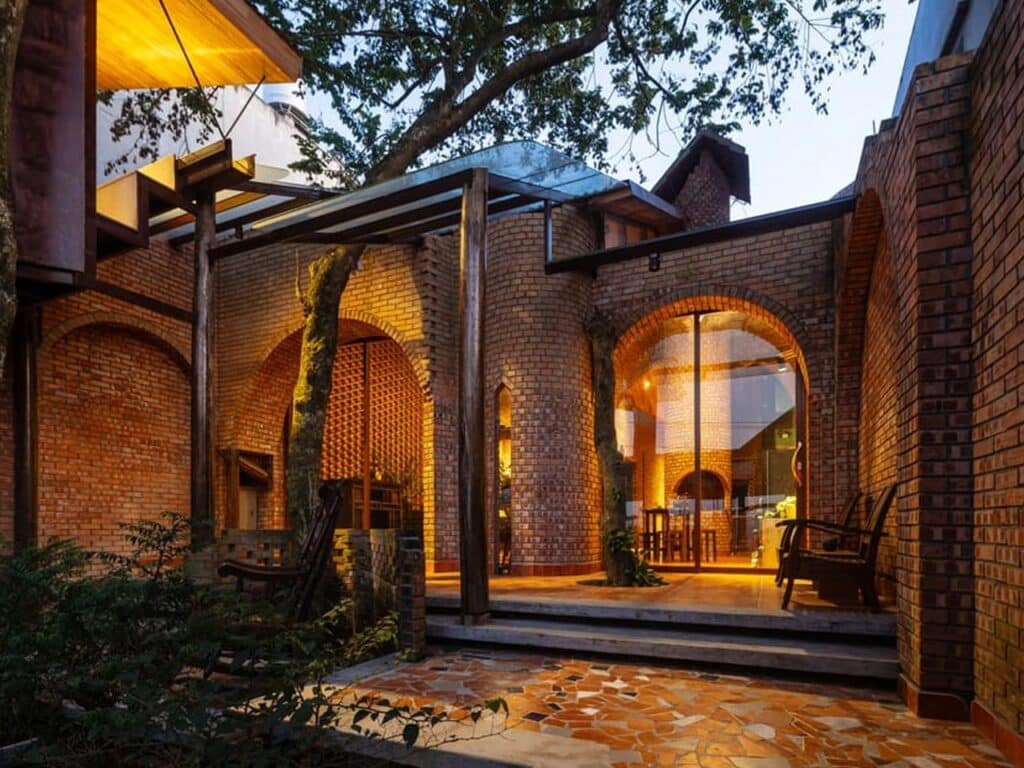 Central courtyard of Nang House shaded by mature trees, blurring boundaries between indoor and outdoor spaces.