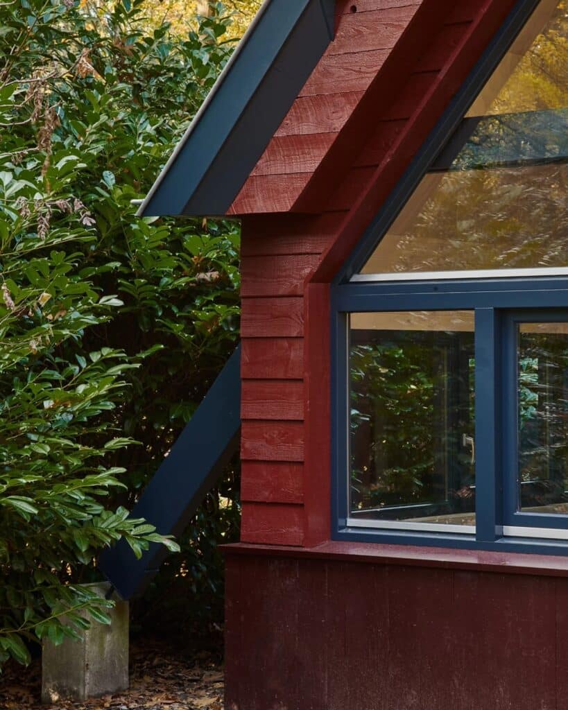 Exterior view of the A-frame Herperduin holiday home surrounded by forest and wildlife habitat.