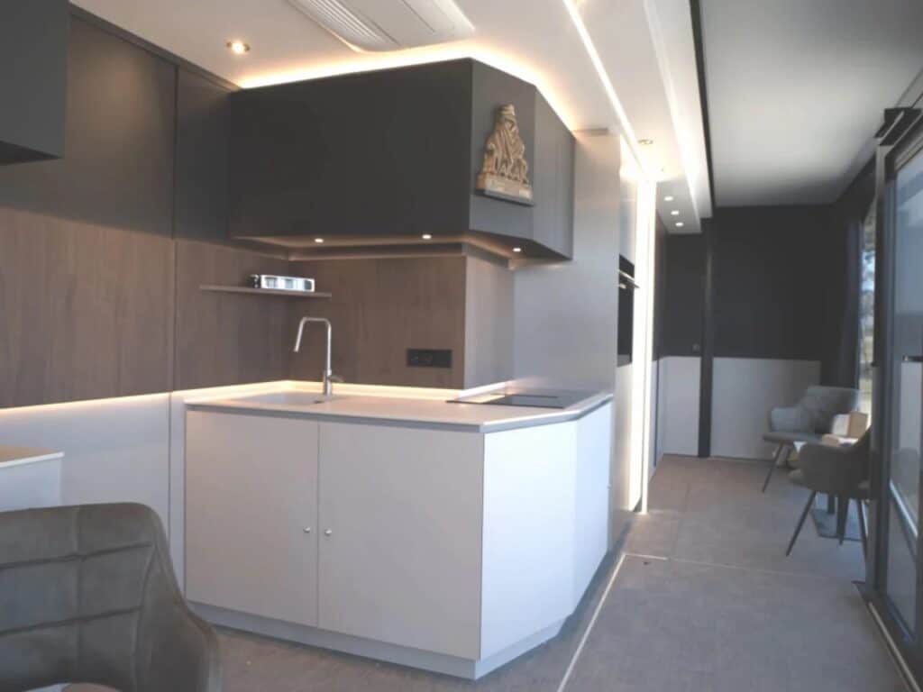 Modern interior of the Shiver x Expandable unit featuring a white minimalist kitchen and warm LED lighting.