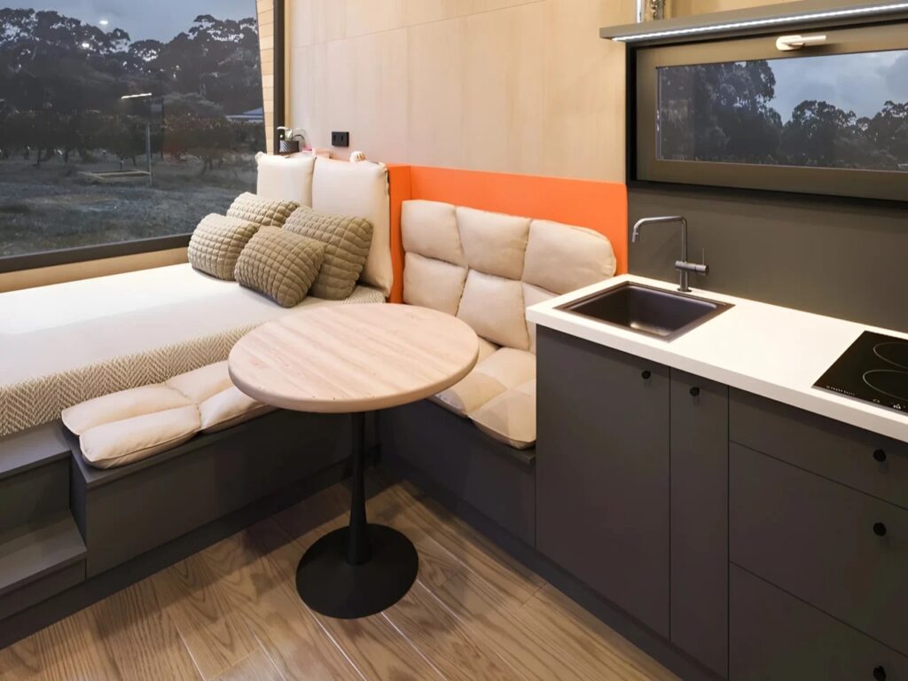 View from the kitchen looking towards the elevated bed area and dining table in Ambra House, showcasing the compact layout.