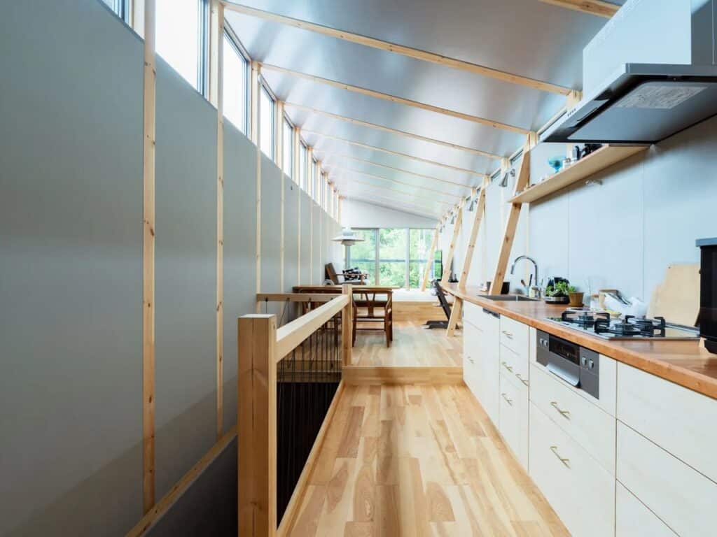 Wide interior shot of the upper floor in Fukasawa House, featuring a linear kitchen, wooden floors, and high clerestory windows.
