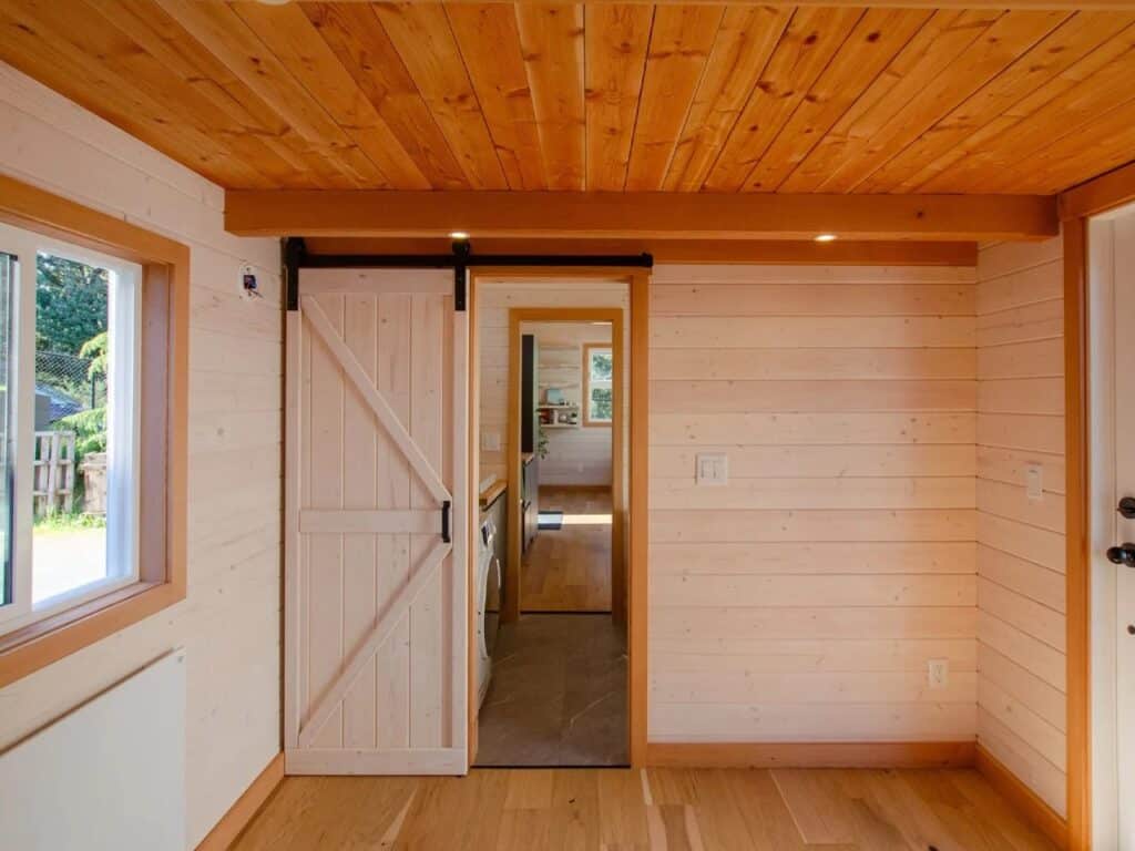 Longitudinal view of a tiny home interior showing the transition from the living area to the bathroom.