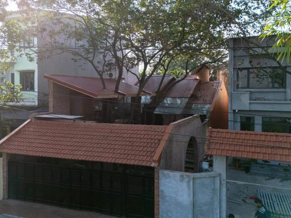 Central courtyard of Nang House shaded by mature trees, blurring boundaries between indoor and outdoor spaces.