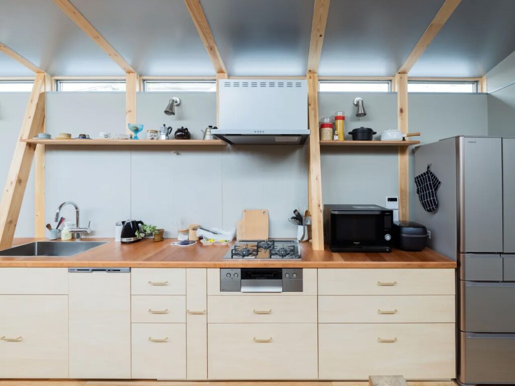 Close-up of a minimalist kitchen in Fukasawa House with light wood cabinets, wooden countertops, and integrated appliances.