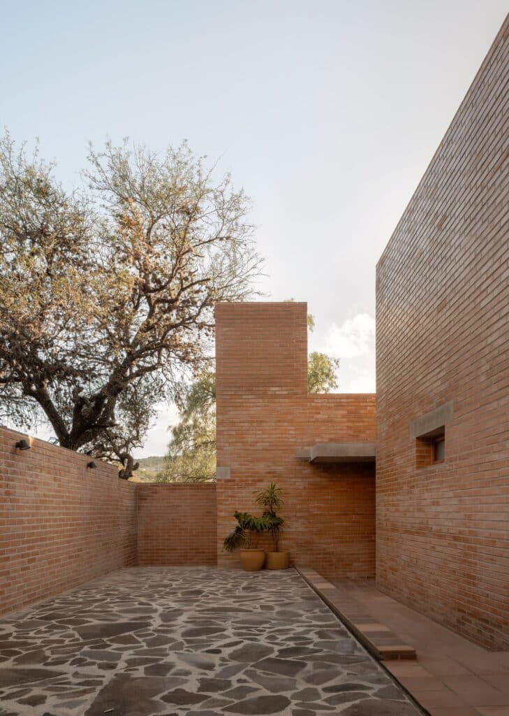 Peroles House in San Miguel de Allende integrates steep terrain, diverse local vegetation, traditional urban planning, and brick construction, showcasing sustainable residential architecture and careful spatial organization.