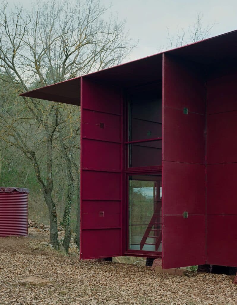 Interior shot showing a steep wooden staircase leading to a loft, surrounded by large folding wall panels opening to the outside.