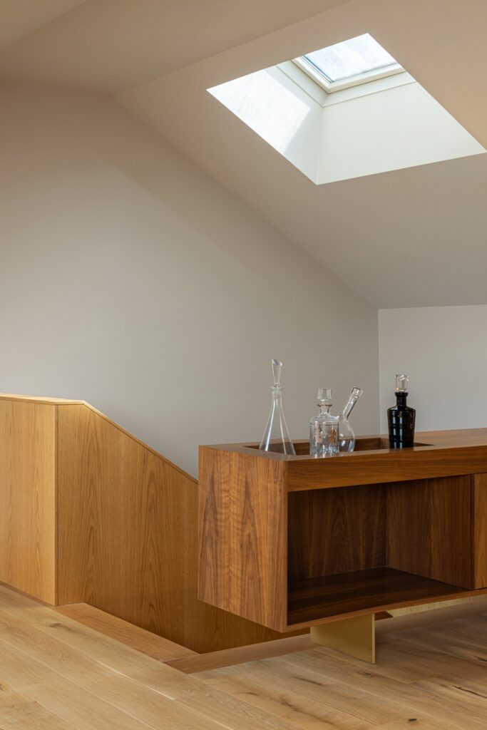 Attic space with a skylight illuminating a custom wooden storage unit and glass decanters.
