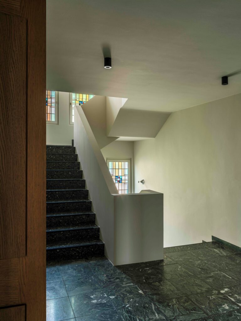 Modern white staircase with dark stone steps and a view of a stained glass window.