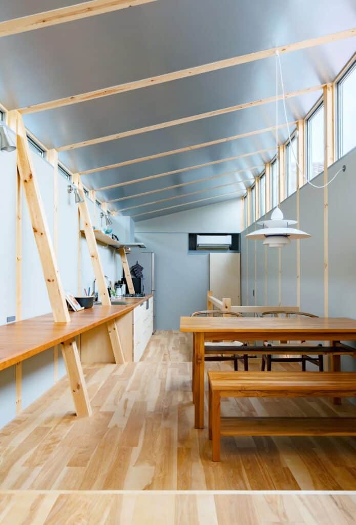 Longitudinal view of the dining and kitchen area in Fukasawa House, showing a wooden dining set and sloped ceiling.