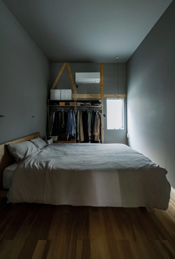 Minimalist master bedroom in Fukasawa House with a high ceiling, grey walls, and an open wardrobe system.