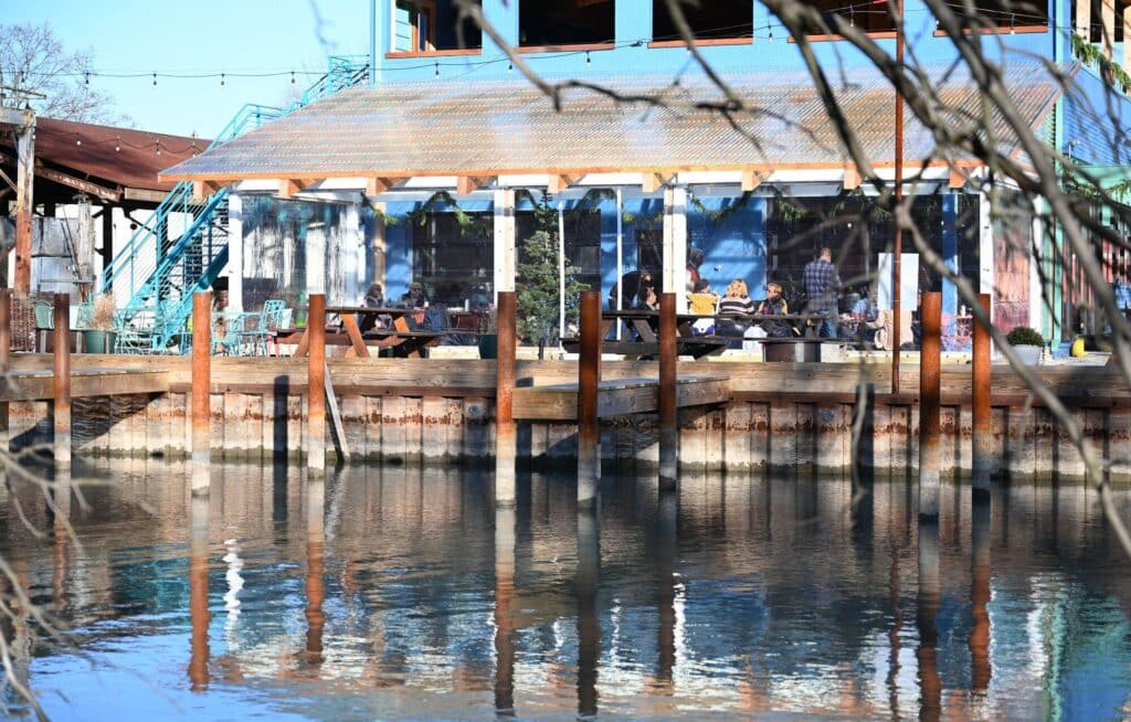 Big Roof architectural project in Detroit combines flexible open-air spaces, seasonal dining areas, wavy roof design, transparent structure, and natural environmental integration.