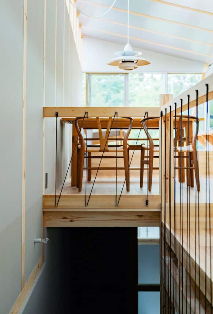 View from the staircase landing in Fukasawa House, looking towards the dining area through a wire-mesh railing.