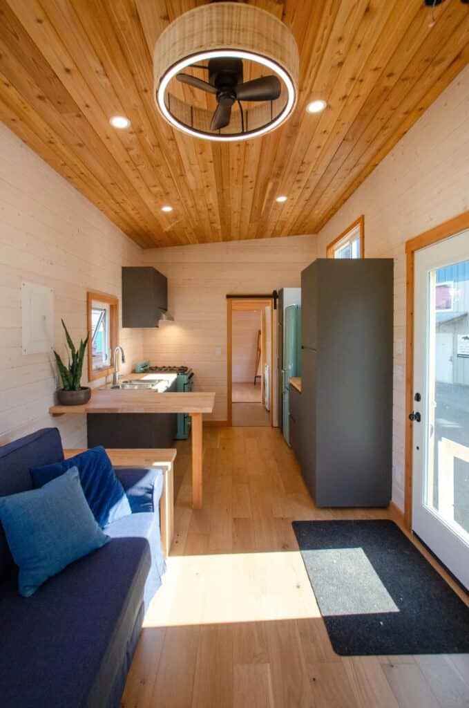 Wide interior shot of the Juniper tiny home from the living room looking toward the kitchen and back door.