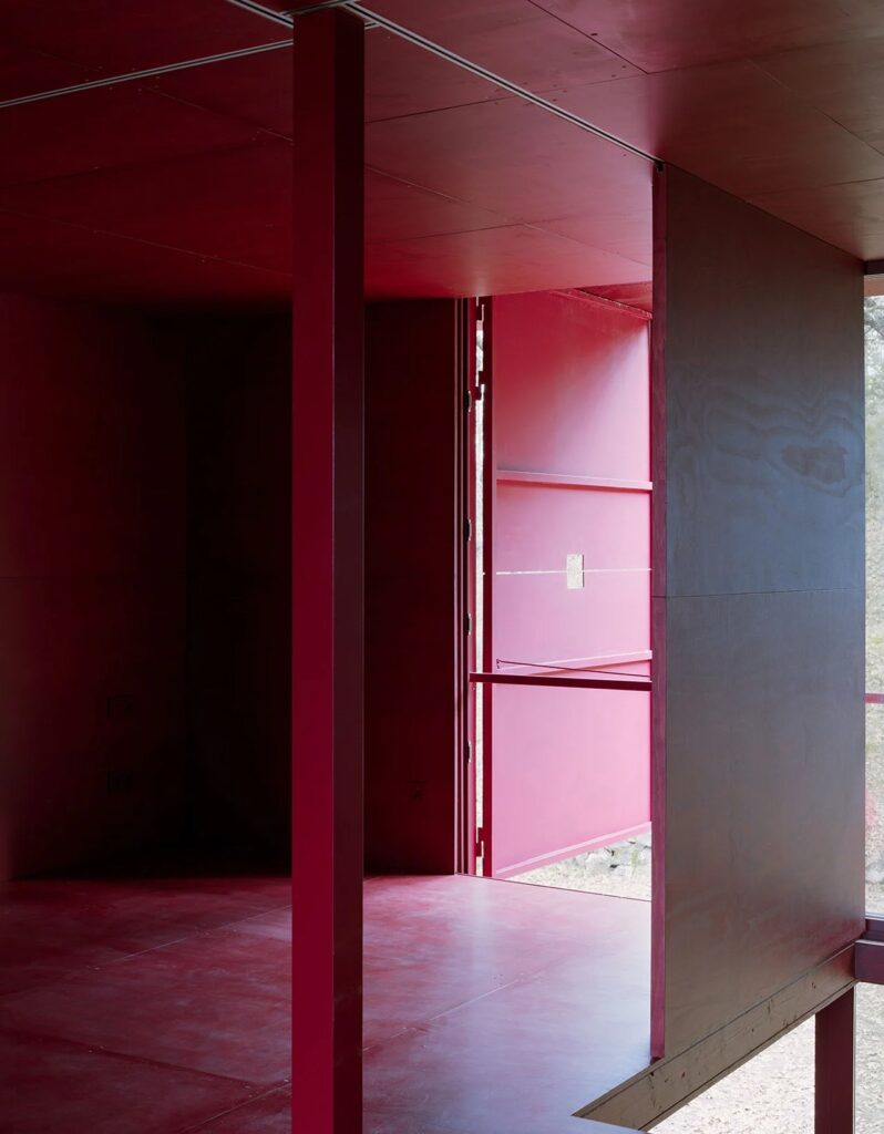 Front view of the Prefab Changeover house with the large two-story folding facade completely open, revealing the glass walls and interior.