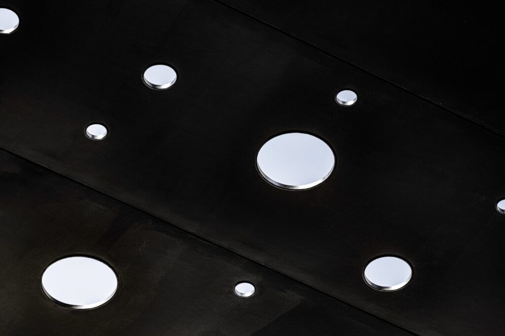 Extreme close-up detail of the George Street Plaza's black metal canopy, showcasing the randomly scattered circular perforations and mirror-lined openings.