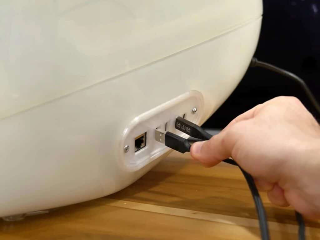 Refurbished Apple iMac G3 featuring original translucent design with modern Mac Mini integration, 4K OLED display, upgraded storage, and enhanced audio system, blending 1990s aesthetics with contemporary performance.