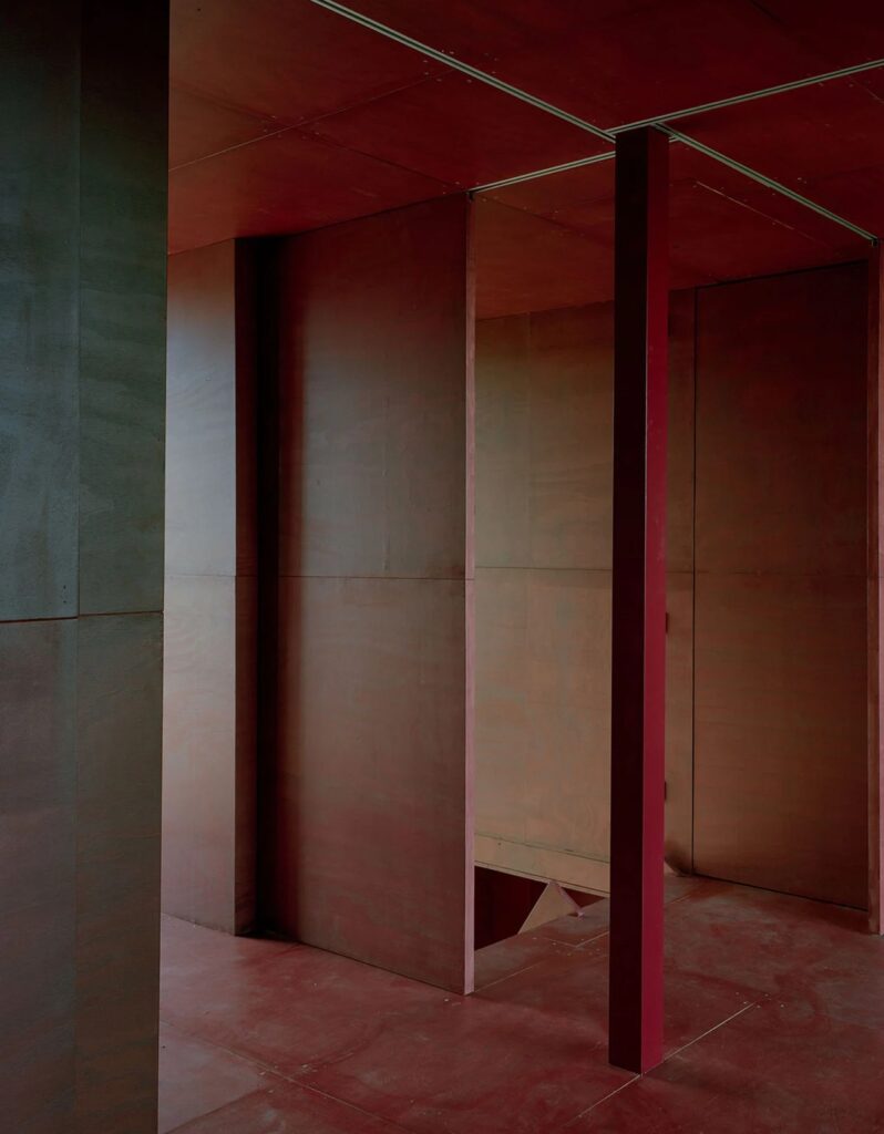 Interior view showing open red folding walls and a dark structural column, emphasizing the indoor-outdoor transition.
