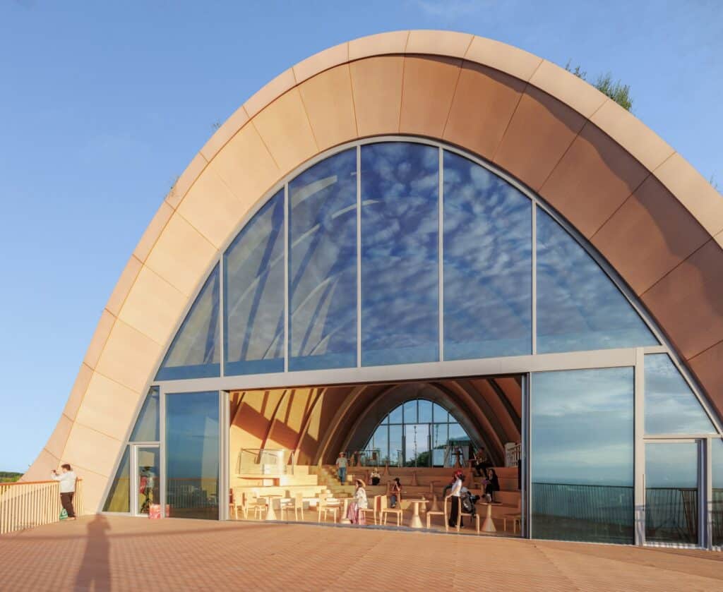 Close-up of the large arched glass opening and wooden terrace of the Pujiang Platform under a clear sky.