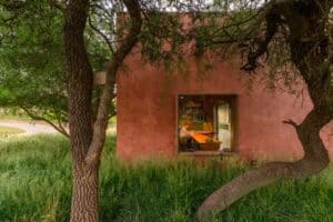 Exterior view of the elevated residential house integrating with natural slope, showing green platform connecting building mass with landscape.