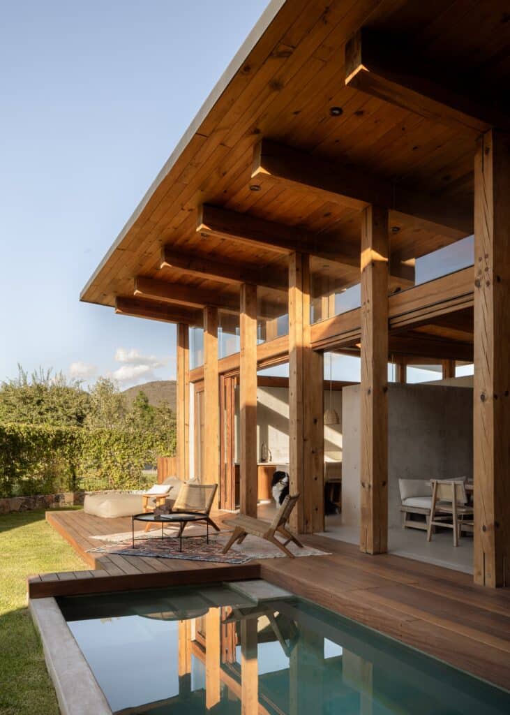 A luxurious wooden deck at Queretaro House featuring a contemporary small pool, stylish lounge chairs, and an exposed timber ceiling structure.