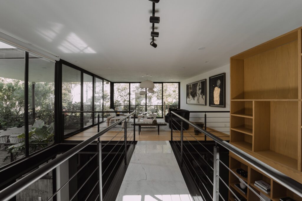 Casa EV residential design in Guadalajara featuring innovative integration of privacy, natural light, wooden materials, interconnected living spaces, central staircase, and landscaped exterior blending indoor and outdoor experiences.