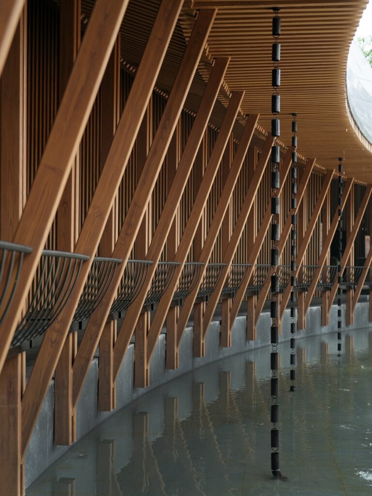 Close-up of architectural rain chains hanging from a wooden canopy at the Zhouzhuang theatre project.