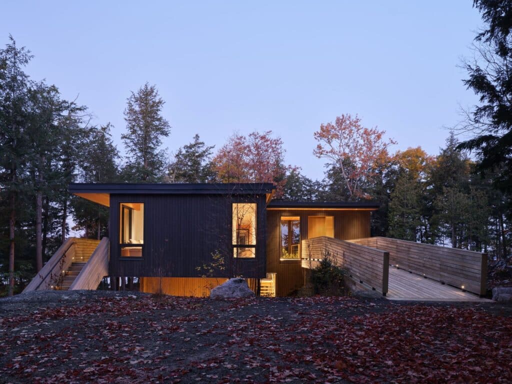 Long Lake Cabin showcases a sustainable architectural design that blends natural wood materials with the surrounding forest while offering elevated spaces and panoramic views connected seamlessly to the landscape.
