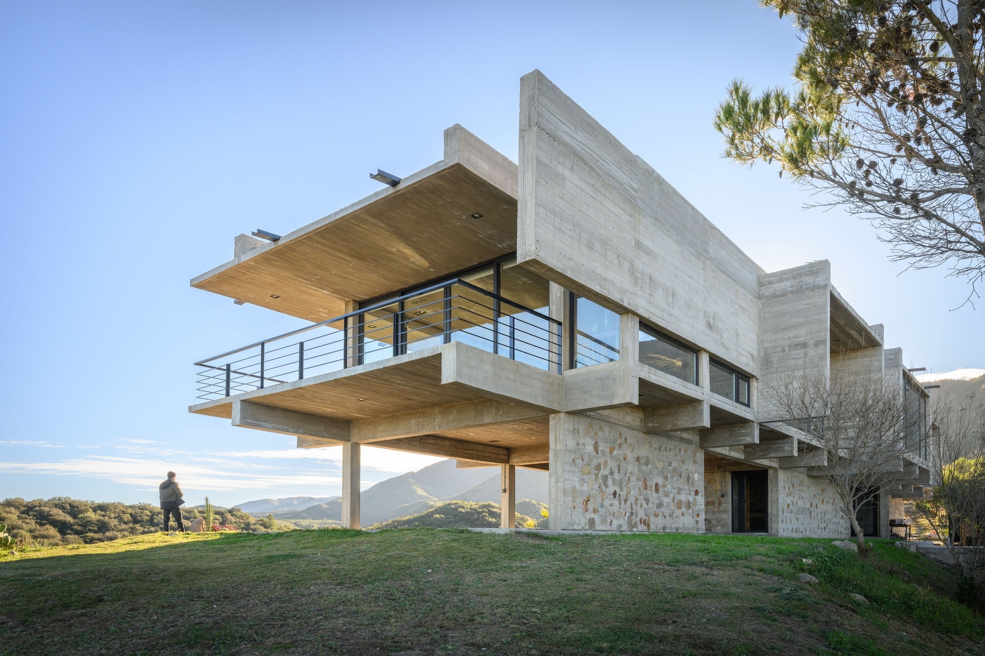 Low-angle architectural shot of a concrete balcony and overhanging roof of a modern house overlooking a valley.