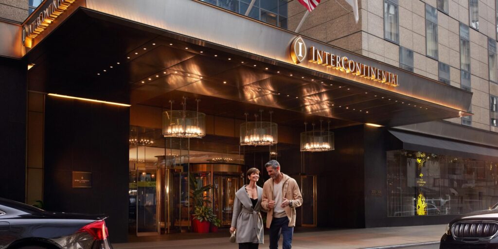 مدخل فندق إنتركونتيننتال في مدينة نيويورك عند الغسق مع زوجين يسيران أمامه.