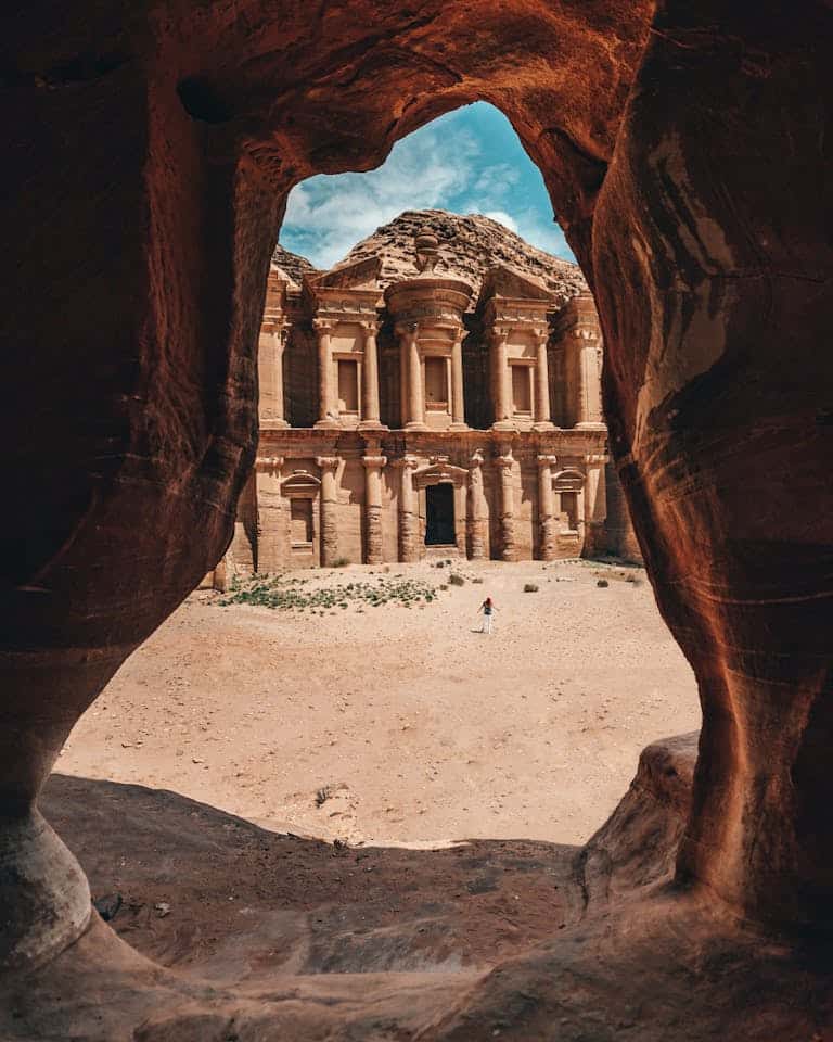 Stunning view of Petra's Monastery framed by a natural cave in Jordan, showcasing ancient architecture.