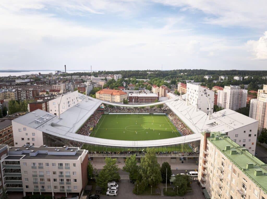 Aerial view of a football stadium integrated within a dense urban neighborhood with surrounding residential buildings.