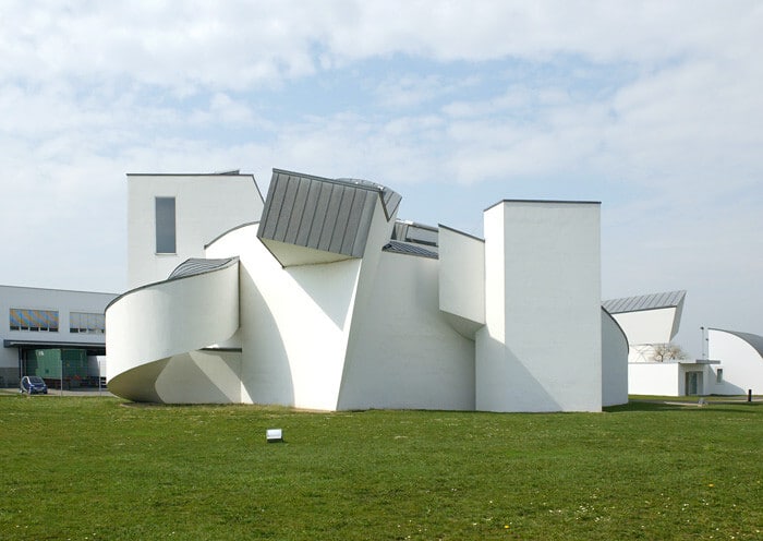 واجهة متحف فيترا للتصميم بأشكاله الهندسية البيضاء المتداخلة وسط ساحة خضراء مفتوحة.