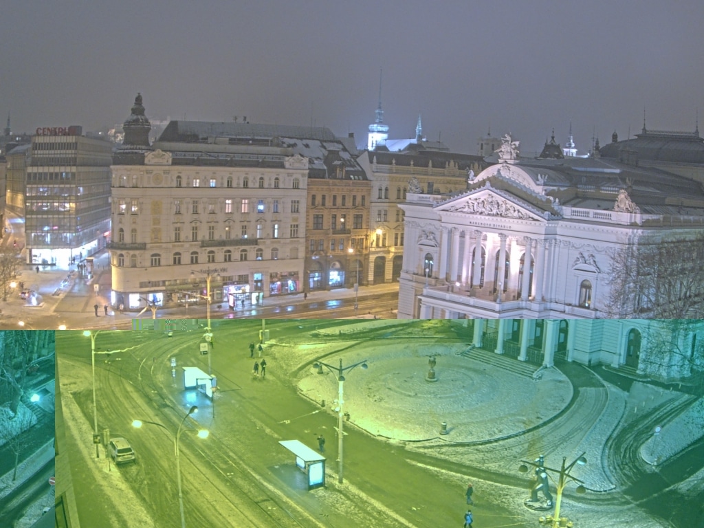 Night view of Malinovsk&eacute;ho n&aacute;měst&iacute; in Brno, Czech Republic, showing the historic National Theatre and surrounding urban fabric under snow, with tram tracks and streetlights illuminating the square.
