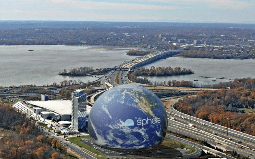 Exterior rendering of the proposed National Harbor Sphere, showing its illuminated spherical structure on the waterfront at dusk.