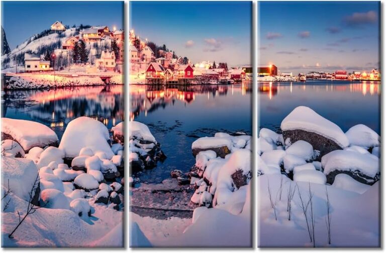 Panoramic view of snow-covered traditional red Rorbuer cabins in Reine, Norway, illuminated at twilight, illustrating the architectural winter slowdown in the Northern Hemisphere.