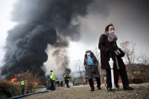 Residents and firefighters at the scene of the January 2026 Jangam fire in Guryong Village, Seoul, where dense informal housing constructed with combustible materials burned amid inadequate emergency access.