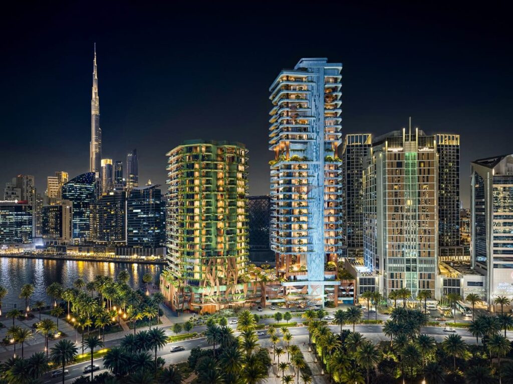 Eywa Way of Water residential towers illuminated at night along Dubai Water Canal, with Burj Khalifa in the background, showcasing regenerative architecture in urban context.