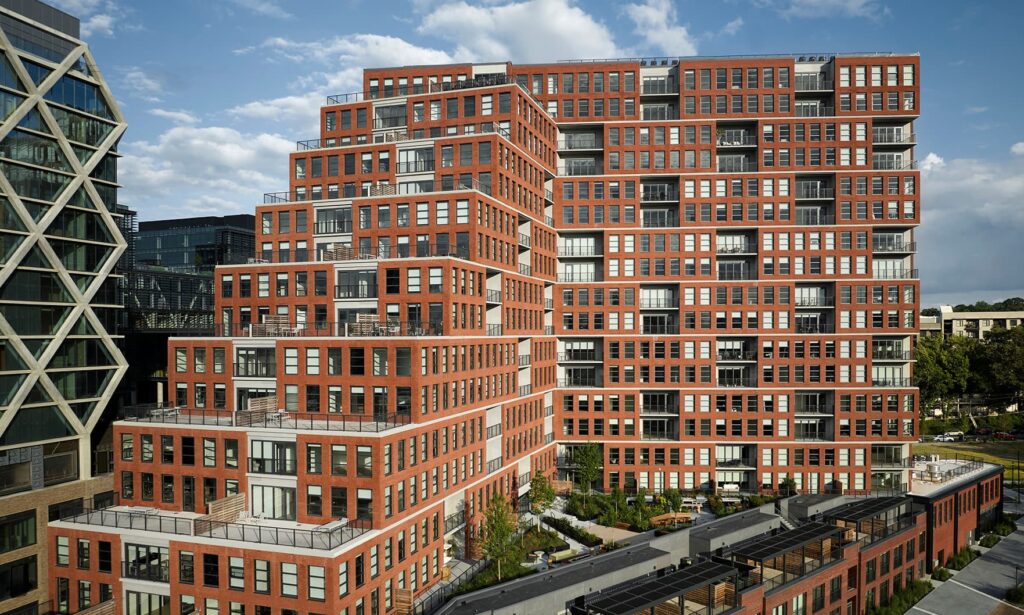 Mixed-use residential building wrapping a historic Romanesque church in Brooklyn, with precast concrete fa&ccedil;ade and sculpted base preserving belfry sightlines.