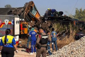 Rescue teams and police at the site of a crane collapse onto a derailed passenger train in Nakhon Ratchasima, Thailand, 2026, with emergency vehicles and debris visible.