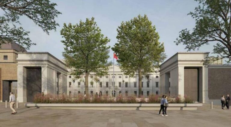 Rendering of the proposed Chinese Embassy in London at Royal Mint Court, showing a restrained classical façade with symmetrical gatehouses, central courtyard, and flagpole, set within an urban plaza with mature trees.