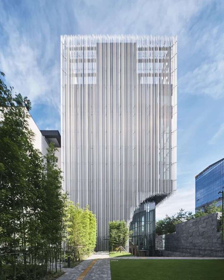 Exterior view of Audeum Seoul, featuring its signature facade of overlapping vertical aluminum pipes that create dynamic light and shadow effects against the Cheonggye Mountains.