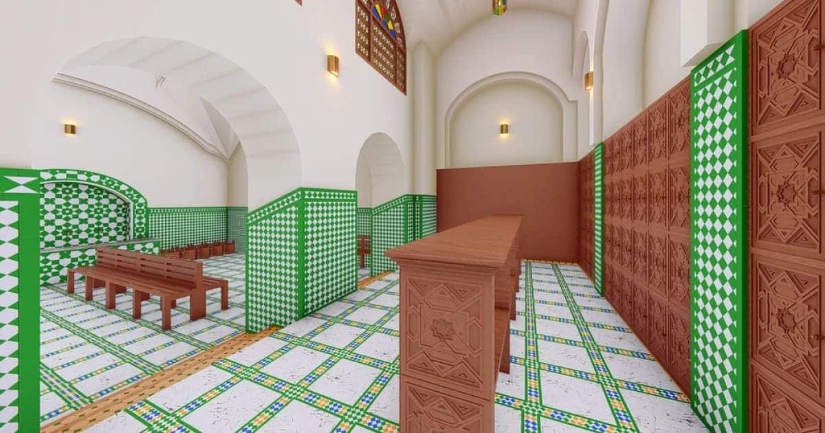 Interior view of a reimagined traditional Moroccan hammam in Fez or Marrakech, featuring arched ceilings, green-and-white zellige tilework, carved cedarwood panels, and benches arranged for social circulation — illustrating sustainable design principles rooted in Islamic architecture.