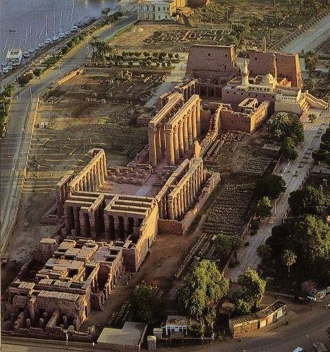 Aerial view of Luxor Temple complex showing Pharaonic columns, Abu Al-Haggag Mosque minaret, and Nile River, illustrating layered civilizations.