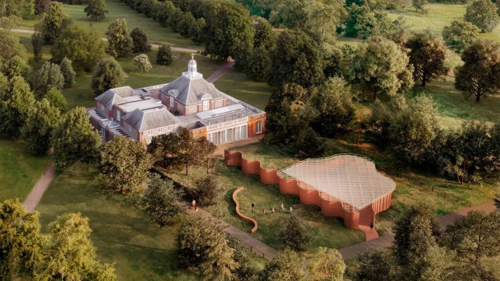 Aerial view of the 2026 Serpentine Pavilion in Kensington Gardens, showing the curved brick structure integrated into the lush landscape near the Serpentine South Gallery.