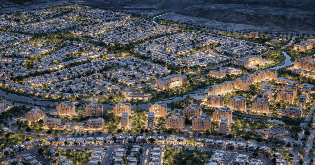 An aerial perspective of a sprawling luxury residential development at twilight, featuring glowing villas, apartment blocks, lush green spaces, and a winding water canal under warm artificial lighting.