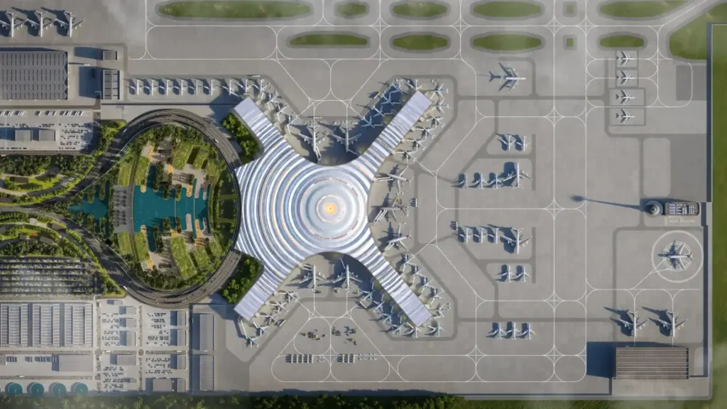 عرض جوي لمحطة مطار جادوكدو الجديد ذات الشكل X والمركز الدائري، محاطة بالمدرجات والمساحات الخضراء.